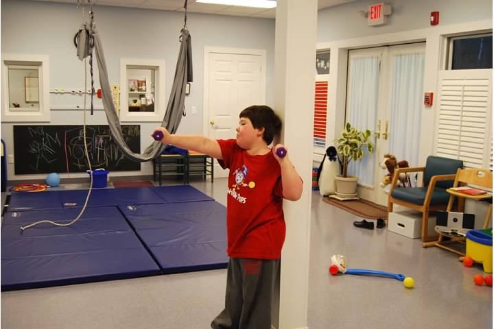 Child using hand weights to strengthen arms. 