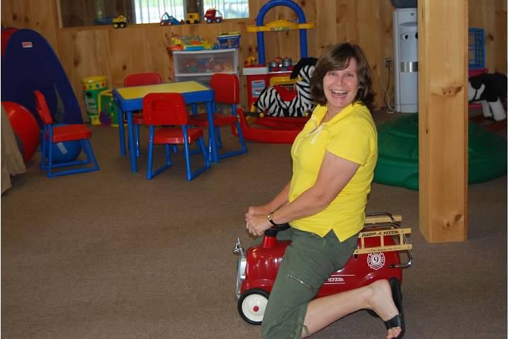 Humorous image of OT in Motion owner Jan Halley playing with toys in physical therapy room.
