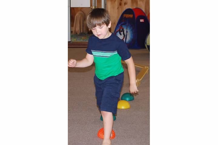 Child walking on low planks and bosu balls to improve balance skills.